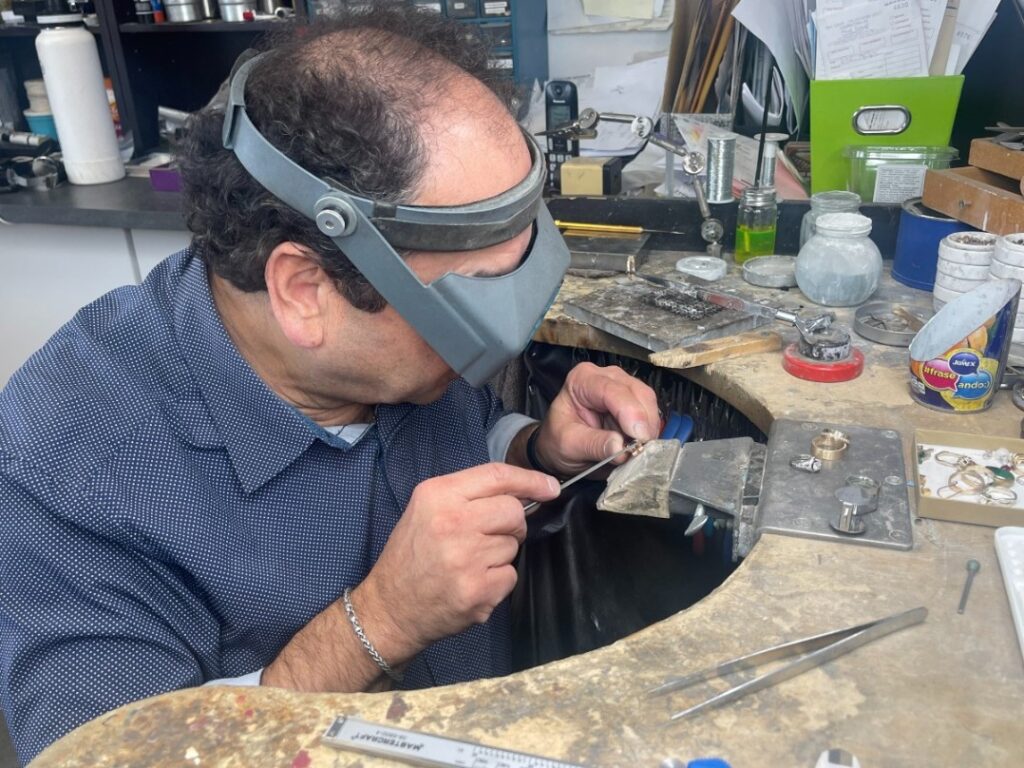 Jewelry craftsman carefully repairing and shaping a ring with precision tools