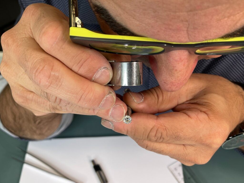 Goldsmith carefully examining a ring with a jeweler’s loupe during custom jewelry work