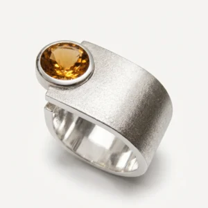 Silver gemstone ring featuring a round amber-colored stone and textured band