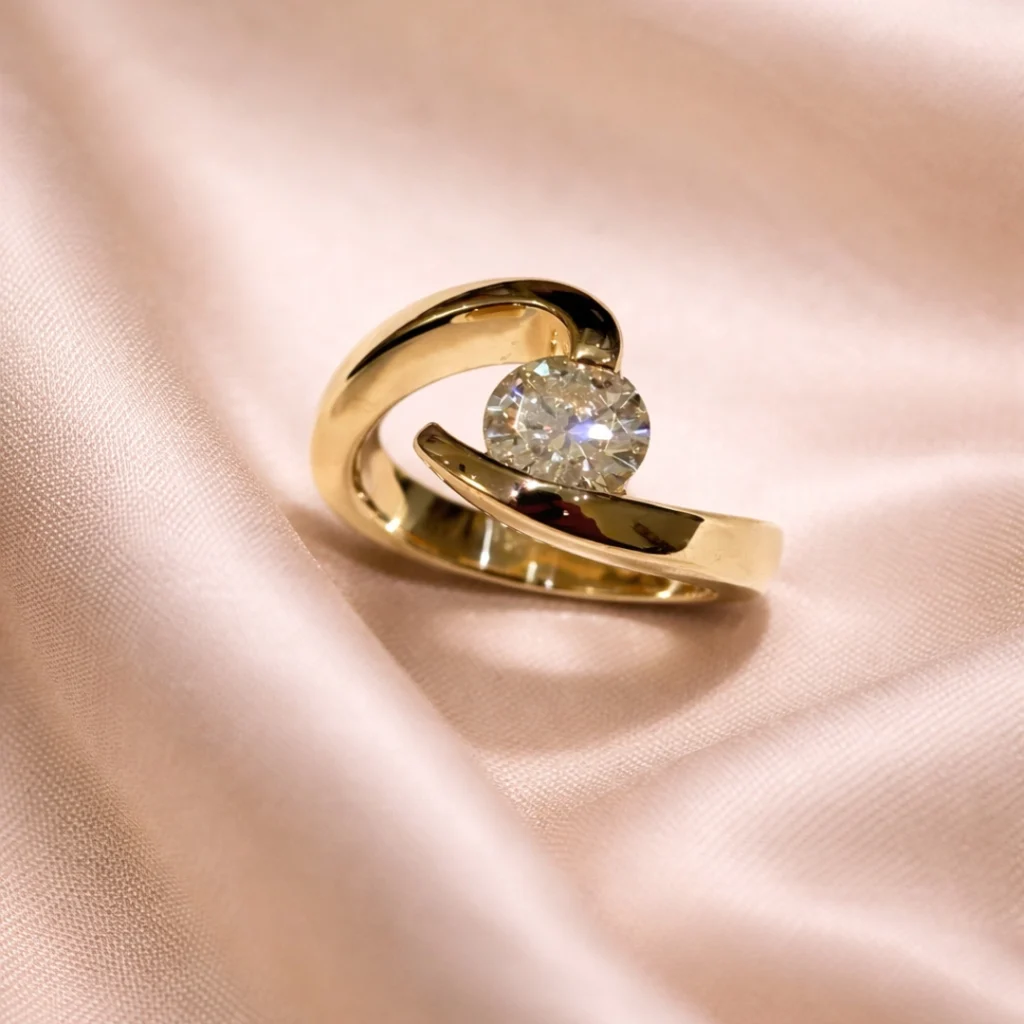 Custom gold engagement ring with a round-cut diamond on soft pink fabric
