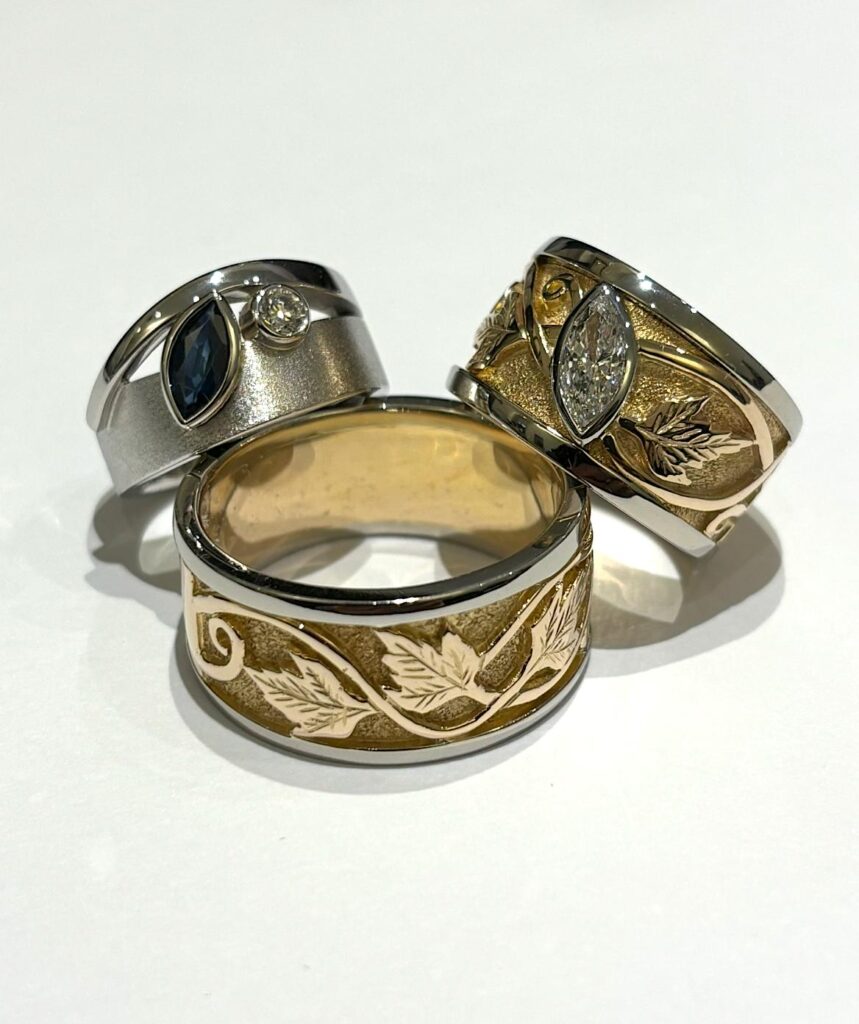 Custom two-tone gold and silver rings with engraved leaf designs and gemstone accents