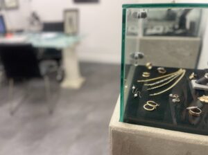 Jewelry pieces displayed in a glass case, including rings, earrings, and delicate gold necklaces.